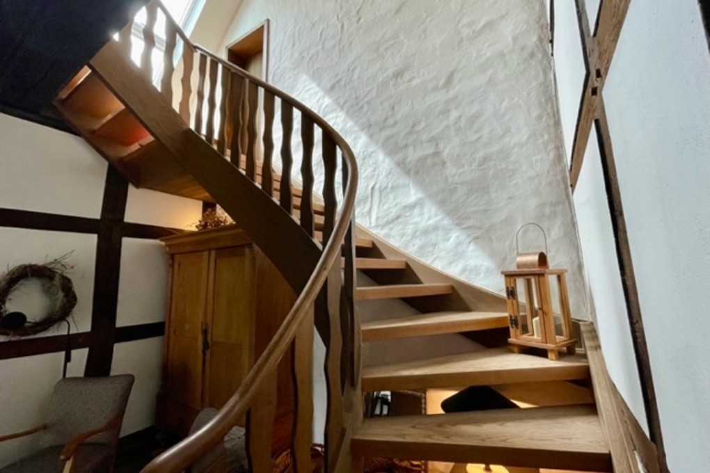 Die formschöne Holztreppe ins Obergeschoss
				