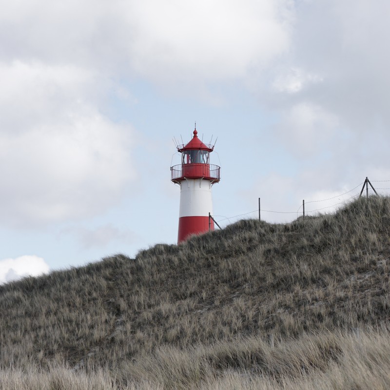 red_and_white_lighthouse_on_green_grass_field_under_white_clouds_during_daytime - ©tkaiser