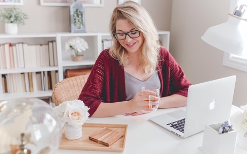 woman_smiling_holding_glass_mug_sitting_beside_table_with_macbook - ©paige_cody